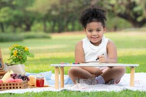 glücklich Familie genießen ein Picknick im das Park, Mädchen sind haben Spaß Zeichnung auf Papier platziert auf das Tisch. foto