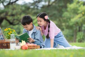 glücklich Familie genießen ein Picknick im das Park, Kinder Sitzung und lesen Bücher. foto