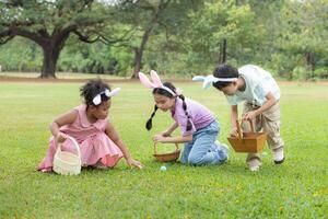 Kinder genießen draussen Aktivitäten im das Park einschließlich ein Lauf zu sammeln schön Ostern Eier. foto