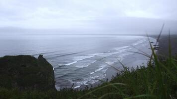 Aussicht mit schön Grün Gras auf Cliff von Meer Küste. Clip. Landschaft von felsig Küste mit Grün Gras und Meer Horizont auf wolkig Tag. Aussicht von Berg Küste zu schön Wellen auf Sommer- Tag foto