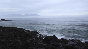 Meer Felsen mit ziehen um Wellen auf Hintergrund wolkig Horizont. Clip. felsig Felsen Stock aus im Wasser auf Strand auf wolkig Tag. schön Seelandschaft mit Felsen im wolkig Wetter foto