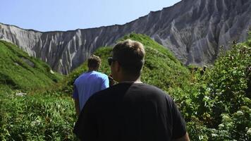 Gruppe von Menschen Spaziergänge entlang Wandern Weg mit Felsen im Sommer. Clip. schön Tourist Route mit Pfad und Grün Gräser zu Weiß Felsen. tolle Weg mit Touristen beim Weiß Felsen auf sonnig Sommer- Tag foto