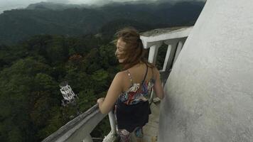 Frau auf historisch Turm im Berge. Aktion. schön Frau auf Überwachung Deck von uralt Turm. Tourist Attraktion beim oben von historisch Turm im Grün Berge foto