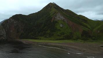 oben Aussicht von wild Küste mit felsig Berge. Clip. Herde von Möwen auf Ozean Ufer auf Hintergrund von tolle Berge. Möwen auf wild Strand auf Berg Insel auf wolkig Tag foto