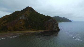 oben Aussicht von tolle Landschaft von Berg Küste auf wolkig Tag. Clip. filmisch Landschaft von Küste mit felsig Grün Berge. schön Meer aus Küste von bergig Norden Insel foto