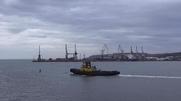 Angeln Boot auf Hintergrund von Hafen im wolkig Wetter. Clip. Angeln Schiff Segel aus von Seehafen in Meer. Angeln Boot Segel in Meer auf wolkig Tag foto