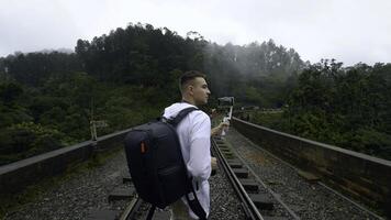 Rückseite Aussicht von ein Mann Tourist nehmen Bilder von Berg bewaldet Landschaft auf Smartphone. Aktion. Wanderer Gehen auf Eisenbahnen. foto