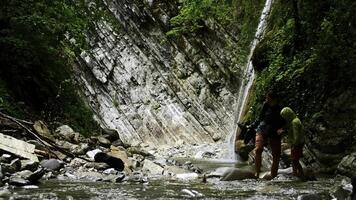 Mutter und Junge Kreuzung Berg kalt Wasser Strom mit Steine. kreativ. Wanderer im malerisch Ort. foto