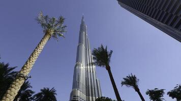 burj Khalifa im das Stadt von Dubai, vereinigt arabisch Emirate. Aktion. niedrig Winkel Aussicht von ein Riese Wolkenkratzer und Palme Bäume. foto