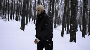 europäisch Mann Stehen im Winter Wald auf ein Winter Tag. Medien. blond Mann erziehen seine Hände zu warm hoch. foto