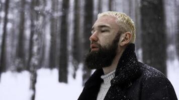 Mann entspannend im das Winter Wald, das Konzept von Einheit mit Natur. Medien. jung blond Mann Denken Über Leben im schneebedeckt Holz. foto