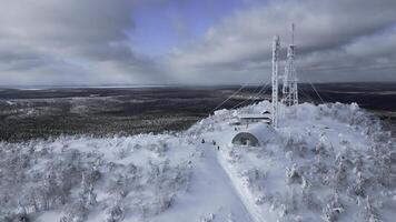 ein Flug Über das dicht Winter sibirisch Wald im das Nachmittag. Clip. Weiß Berg und ein gefroren Wetter Turm auf es ist oben. foto