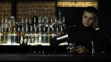 das Prozess von vorbereiten ein alkoholisch Cocktail beim das Bar. Medien. jung männlich Barmann beim arbeiten. foto