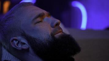 Porträt von ein schläfrig Mann mit Neon- Beleuchtung. Medien. jung bärtig Mann Gefühl müde und versuchen zu schlafen. foto