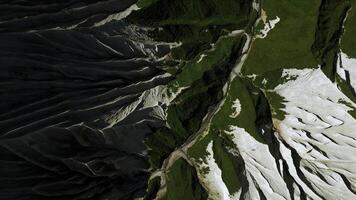 Antenne oben Nieder Aussicht von ein Berg oben. Clip. Grün Sommer- Gras und Weiß steinig Pisten. foto