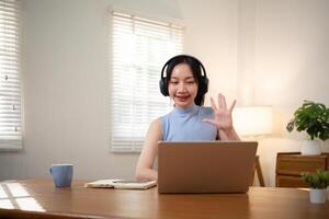 glücklich jung Frau asiatisch im Kopfhörer und Laptop Herstellung Anmerkungen, Mädchen Schüler reden durch Video Konferenz Forderung, online Ausbildung foto