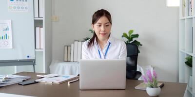 asiatisch Geschäft Frau mit Laptop zu Analyse Graph finanziell Budget Bericht und Planung zum Zukunft im Büro Schreibtisch foto