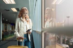 Reisender Frau asiatisch im Flughafen und Gepäck zum Urlaub, Lächeln und reden auf das Telefon prüfen Einsteigen Fahrkarte. weiblich Reisender mit Koffer, International und Abfahrt mit Reisepass und Ausflug foto