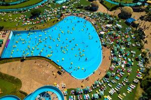 oben Aussicht von Menschen entspannend im das Schwimmbad auf Gelb aufblasbar Kreise und Sonne Betten auf das Strand foto