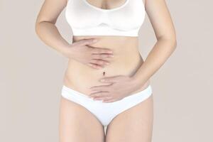 Frau im Weiß Unterwäsche mit Menstruation- Schmerzen ist halten ihr Schmerz Bauch, Frau mit Bauch Schmerzen und Bauch Krämpfe foto