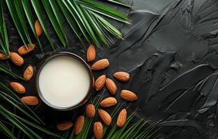 ai generiert Mandel Milch im Glas und Mandeln mit Palme Blätter auf schwarz Hintergrund foto