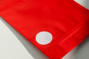 Weiß kreisförmig Aufkleber auf rot poly Mailer Briefumschlag mit natürlich Schatten. foto