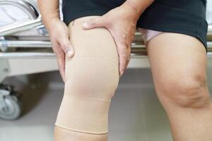 asiatische Seniorin mit elastischer Kniebandage zur Schmerzlinderung. foto