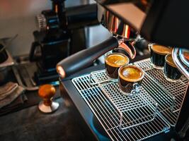 Fachmann Espresso Maschine während vorbereiten zwei Espresso Schuss Glas im ein Kaffee Geschäft. Espresso Schuss mit Kaffee Creme foto