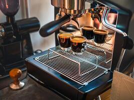 Fachmann Espresso Maschine während vorbereiten zwei Espresso Schuss Glas im ein Kaffee Geschäft. Espresso Schuss mit Kaffee Creme foto