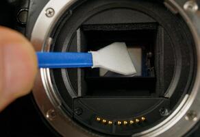 Techniker reinigt Sensor von Digital Kamera von Staub und Schmutz foto