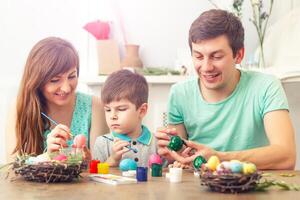 Mutter, Vater und Sohn sind Gemälde Eier. glücklich Familie sind vorbereiten zum Ostern. foto
