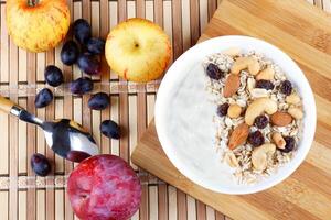 natürlich Joghurt mit hausgemacht Granola und Nüsse im Keramik Schüssel auf ein Tabelle oben Aussicht foto