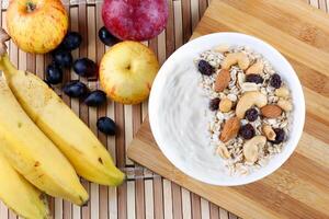 natürlich Joghurt mit hausgemacht Granola und Nüsse im Keramik Schüssel auf ein Tabelle oben Aussicht foto