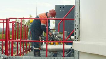 Mitarbeiter von das Gas Bahnhof im ein schützend medizinisch Maske, Gas Verteilung Bahnhof wendet sich oder schraubt ab das Gas liefern Ventil. Arbeit von ein Gas Produktion Arbeiter beim ein Gas Bahnhof. foto