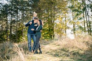 Mama Umarmungen Papa mit ein wenig Mädchen auf seine Schultern berühren seine Stirn mit ihr Stirn foto