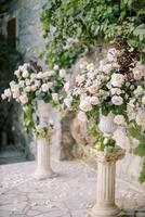 Hochzeit Halbbogen von Blumensträuße von Blumen auf Sockel in der Nähe von ein Stein Mauer im das Garten foto