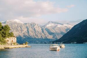 Motor- Boote sind festgemacht im das Meer im Vorderseite von uralt Häuser auf das Küste beim das Fuß von das Berge foto