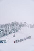 Skifahrer Reiten bergauf auf ein Ski Aufzug über ein schneebedeckt Nadelbaum Wald foto