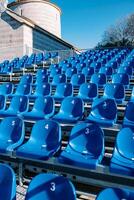 Reihen von Blau Sitze im ein Stadion in der Nähe von ein uralt Kirche foto