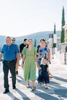 Erwachsene mit ein wenig Mädchen im ein Hexe Kostüm mit ein Korb gehen Nieder das Straße foto