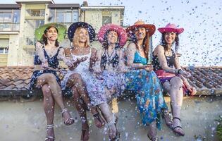 Gruppe von freunde auf Ferien Sitzung auf das Dächer während weht Konfetti foto