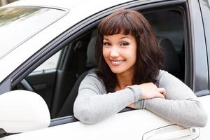 glücklich Inhaber von ein Neu Wagen. jung ziemlich Frau Treiber lächelnd zu Sie foto