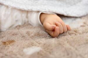 ein richtig Hand von Schlafen asiatisch Baby auf das Teppich foto