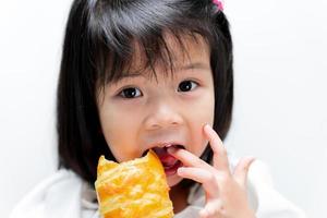 Das Gesicht eines glücklichen Kindes leckte den Finger, der das lange Brot hielt. Kinder aßen die langen Brötchen mit Genuß. foto