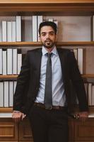 junger gutaussehender Geschäftsmann aus dem Nahen Osten in Anzug und Krawatte, der im Arbeitsbüro steht. Geschäftskonzept foto