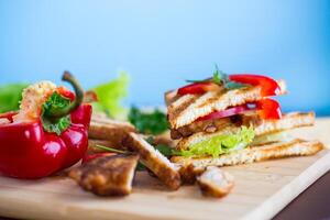 gebraten Toast mit Huhn, Salat, Grüns auf ein hölzern Tabelle foto