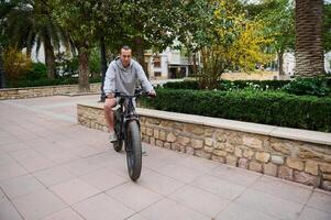 voll Länge Porträt von ein gut aussehend kaukasisch Mann mieten elektrisch Fahrrad, Reiten im das Stadt. Fahrrad Teilen Stadt Bedienung foto