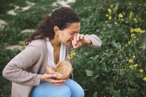 jung Frau Niesen während Versammlung Wildblumen im das Wiese draußen, Leiden von Allergie im das Frühling Zeit. foto