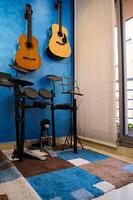 modern Innere von ein Musik- Studio zum Zuhause verwenden. akustisch nd elektrisch Gitarren hängend auf Blau Farbe Mauer und Trommel Satz. Hobbys und Freizeit. Musiker Zimmer zum spielen und Lernen Musik- foto