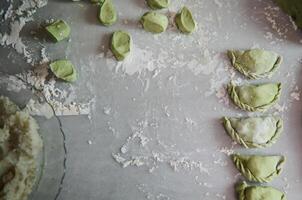 oben Sicht. Essen Hintergrund mit geformt roh Knödel, ukrainisch Warennyky und Italienisch Ravioli auf ein bemehlt Marmor Oberfläche von Küche Tisch. traditionell Küche. Essen Hintergrund. Kopieren Werbung Raum foto